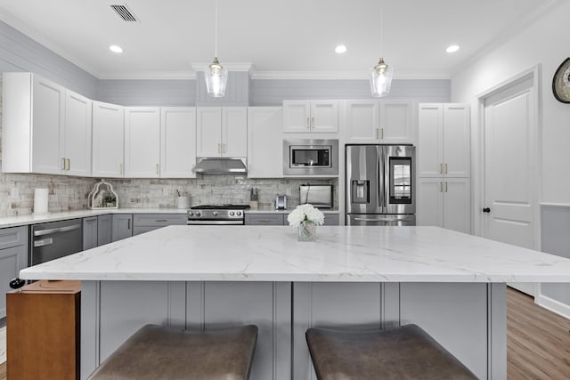 1233 Elderflower Dr, Niceville, FL 32578 - kitchen featuring stainless steel appliances, under cabinet range hood, decorative backsplash, a kitchen bar, and light stone counters