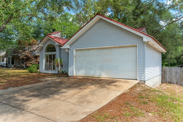 garage featuring fence and concrete driveway