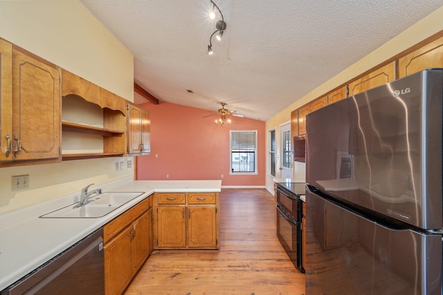 kitchen featuring appliances with stainless steel finishes, lofted ceiling, light wood-style flooring, a textured ceiling, and a peninsula