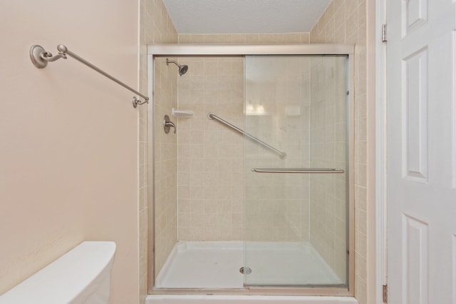 full bathroom with a shower stall, toilet, and a textured ceiling