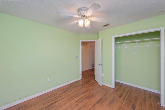 unfurnished bedroom with wood finished floors, baseboards, a closet, a textured ceiling, and a ceiling fan