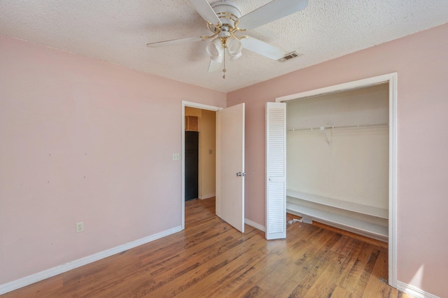 unfurnished bedroom with baseboards, wood finished floors, a closet, a textured ceiling, and ceiling fan