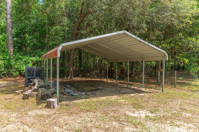 view of yard with a detached carport, fence, and a view of trees