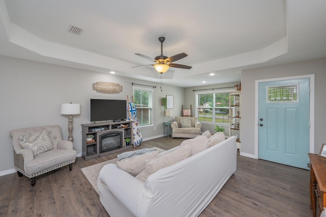 living area with a tray ceiling, wood finished floors, baseboards, recessed lighting, and a ceiling fan