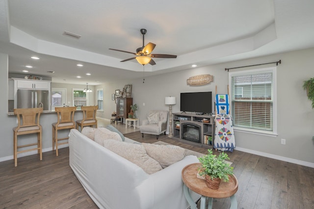 living room with baseboards, a raised ceiling, recessed lighting, and dark wood-style flooring
