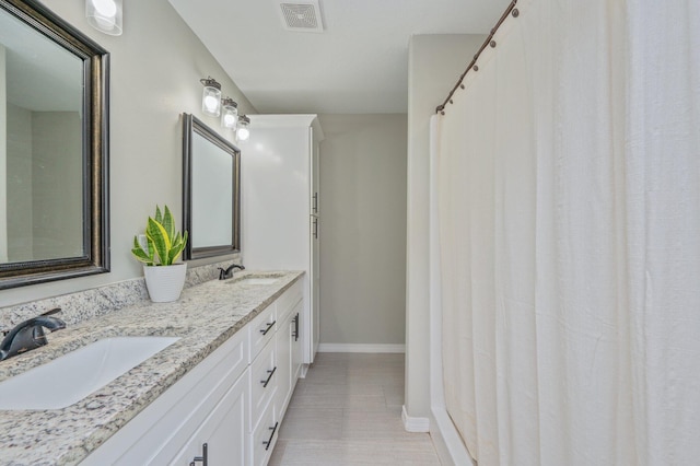 full bath with baseboards and double vanity
