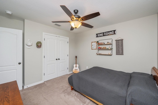 carpeted bedroom featuring a closet, baseboards, and a ceiling fan