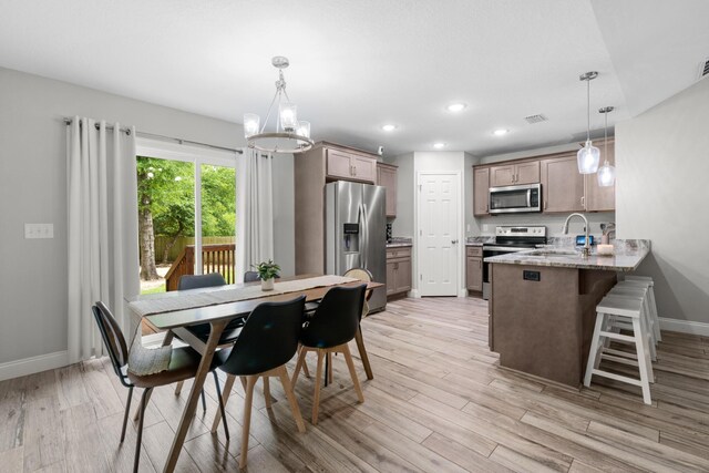 dining area featuring light wood-style floors, baseboards, a chandelier, and recessed lighting