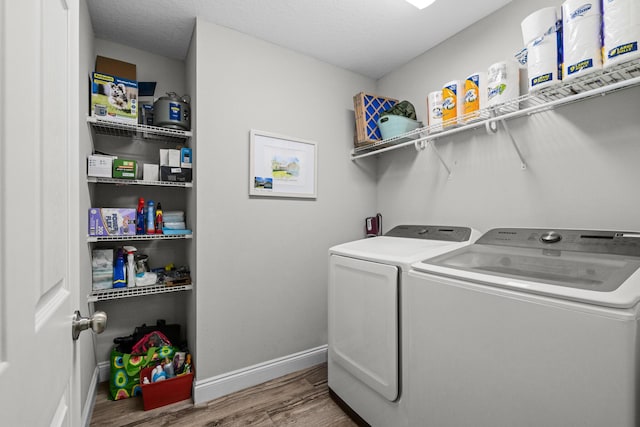 clothes washing area with independent washer and dryer, wood finished floors, and baseboards