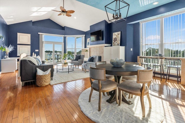 1280 Mahogany Mill Rd, Pensacola, FL 32507 - dining space with a ceiling fan, wood-type flooring, high vaulted ceiling, a chandelier, and a tiled fireplace