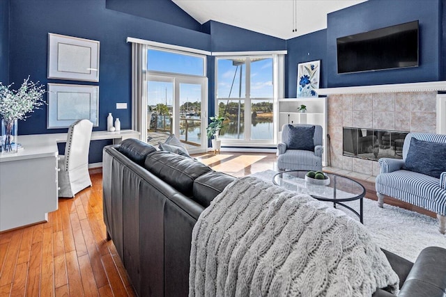 1280 Mahogany Mill Rd, Pensacola, FL 32507 - living room with vaulted ceiling, wood-type flooring, a tiled fireplace, baseboard heating, and baseboards