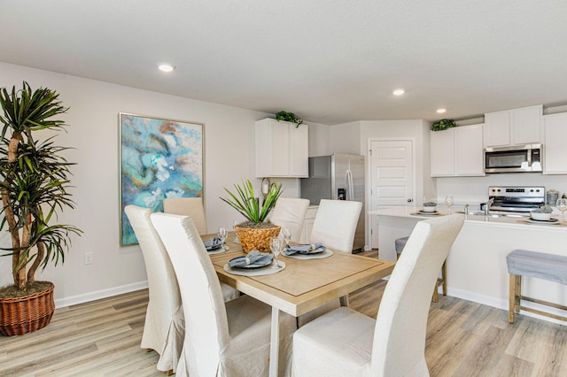 dining room featuring light wood-type flooring, recessed lighting, and baseboards