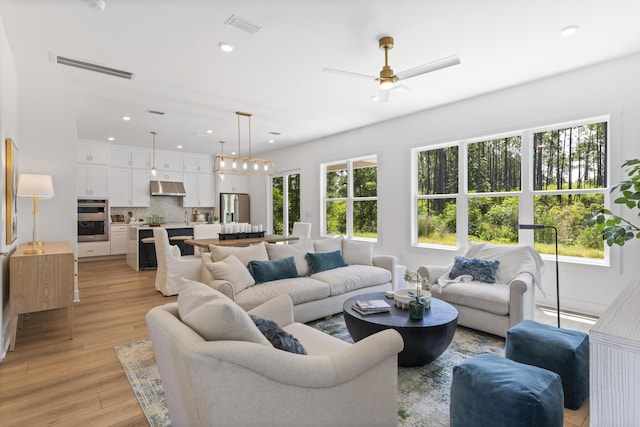 living room with a ceiling fan, recessed lighting, and light wood-type flooring