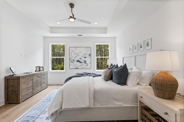 bedroom with a raised ceiling, light wood-style flooring, a ceiling fan, baseboards, and recessed lighting