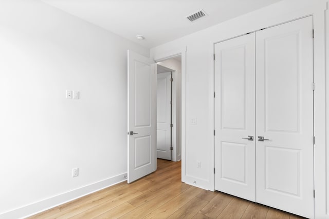 unfurnished bedroom with light wood-type flooring, a closet, and baseboards