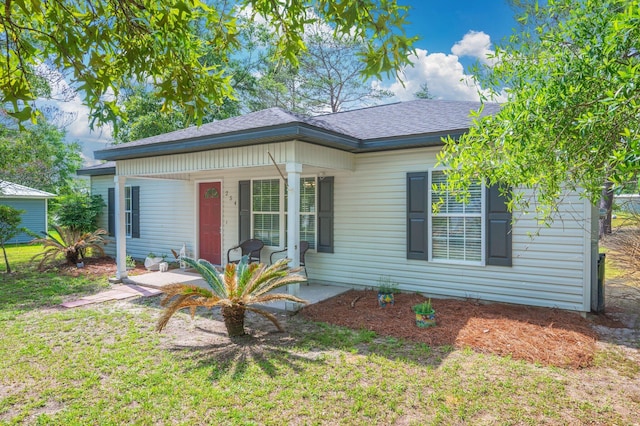 view of front of house featuring a porch, a shingled roof, and a front lawn