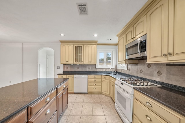 7118 Singleton Cir Unit A, Panama City, FL 32404 - kitchen featuring white appliances, arched walkways, backsplash, a sink, and dark stone counters