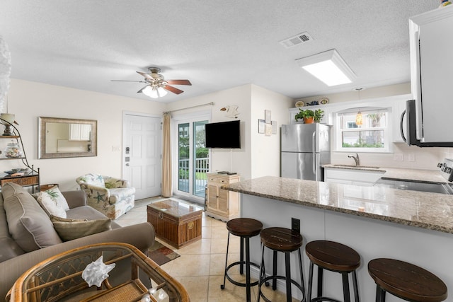 11 Beachside Dr Unit 613, Santa Rosa Beach, FL 32459 - kitchen featuring freestanding refrigerator, range with electric cooktop, a peninsula, light stone countertops, and a textured ceiling
