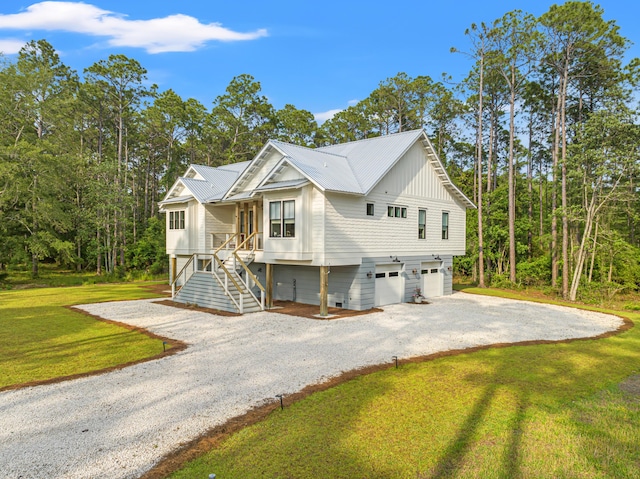 view of front facade with an attached garage, gravel driveway, stairway, a front lawn, and metal roof