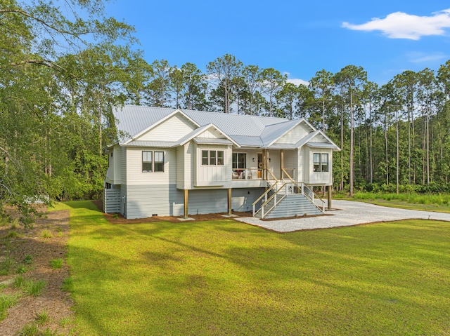back of house featuring stairway, a lawn, covered porch, and metal roof