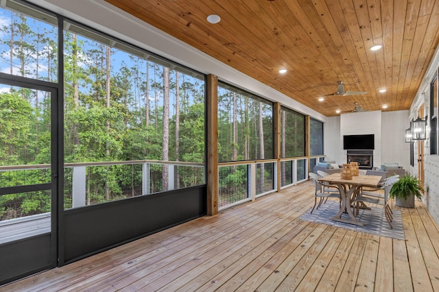 sunroom featuring outdoor dining area, a fireplace, and plenty of natural light
