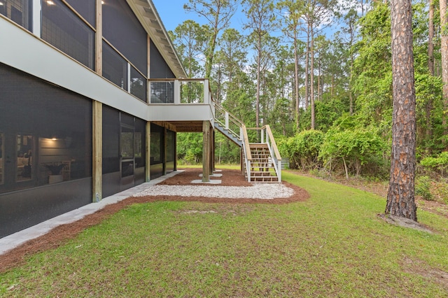 view of green lawn featuring a sunroom and stairs