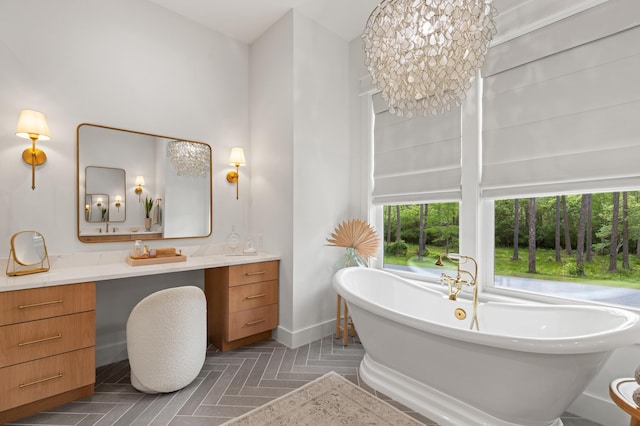 bathroom featuring vanity, a freestanding bath, a chandelier, and baseboards