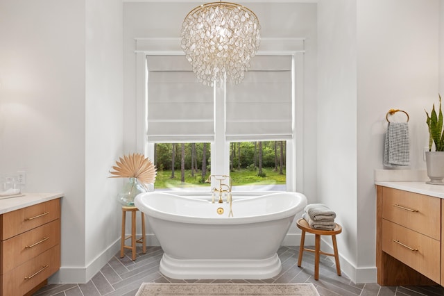 bathroom featuring vanity, baseboards, a freestanding tub, and a chandelier