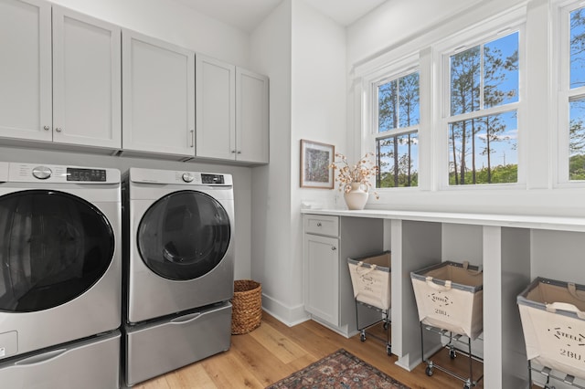 laundry room featuring cabinet space, independent washer and dryer, plenty of natural light, and light wood finished floors