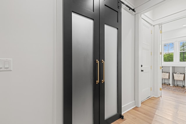 hallway featuring light wood-style flooring and a barn door