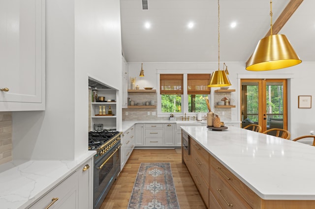 kitchen featuring open shelves, range with two ovens, plenty of natural light, and high vaulted ceiling