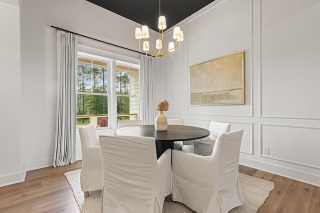 dining space featuring a chandelier, wood finished floors, and a decorative wall