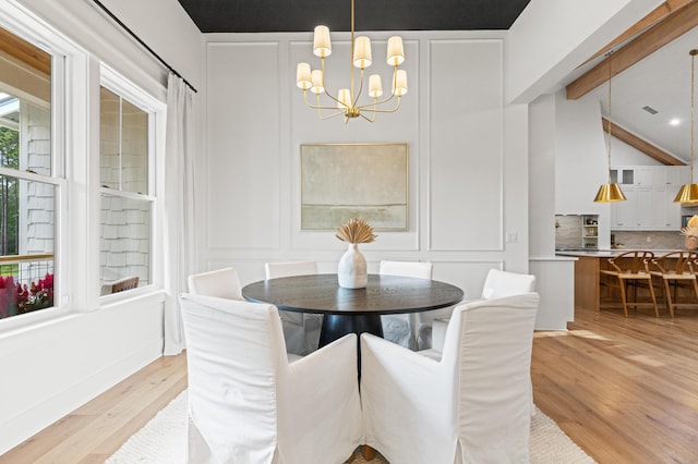 dining room with a chandelier, a decorative wall, and light wood-style flooring