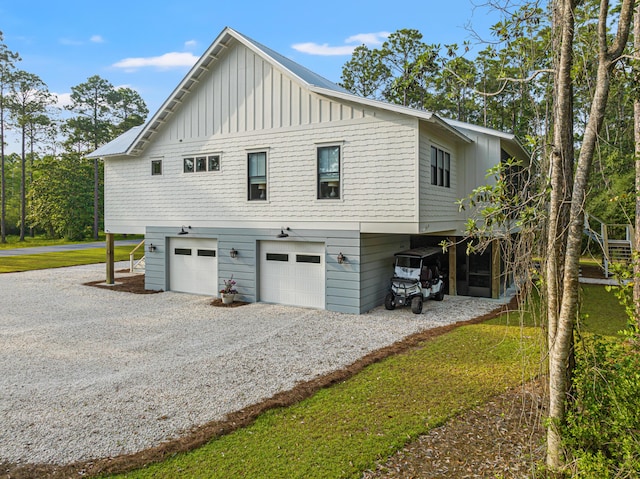 view of side of home with board and batten siding, gravel driveway, an attached garage, and a carport