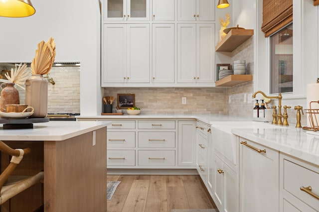 kitchen featuring open shelves, white cabinetry, light wood-style flooring, tasteful backsplash, and glass insert cabinets