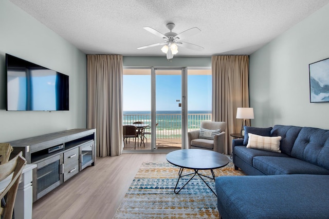 1200 Scenic Gulf Dr Unit B507, Miramar Beach, FL 32550 - living room with a textured ceiling, light wood finished floors, a ceiling fan, and a water view