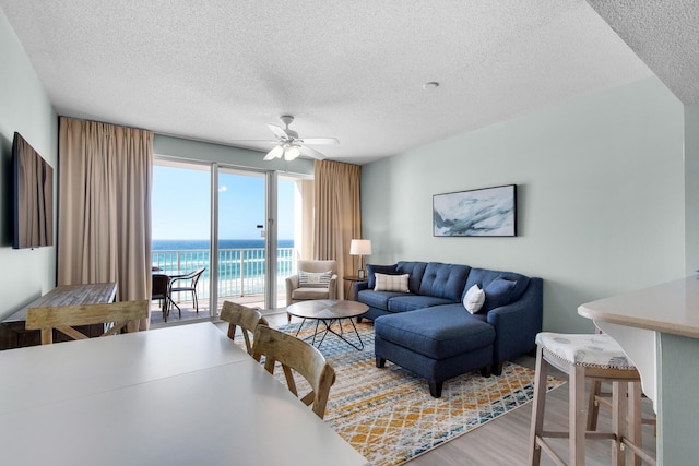 1200 Scenic Gulf Dr Unit B507, Miramar Beach, FL 32550 - living area featuring a textured ceiling, ceiling fan, a water view, and wood finished floors