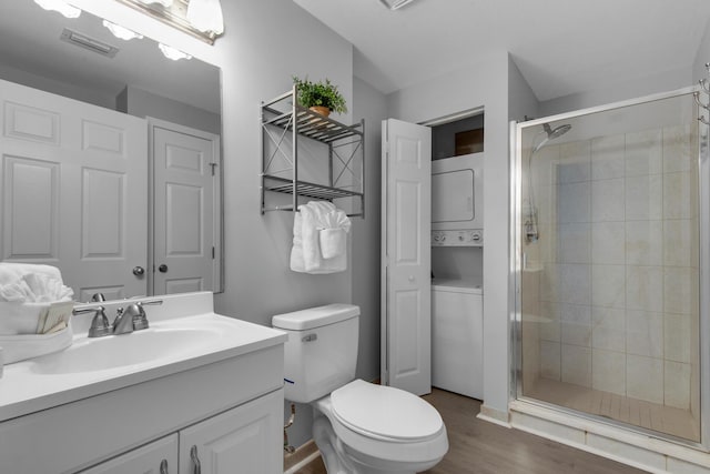 1200 Scenic Gulf Dr Unit B507, Miramar Beach, FL 32550 - bathroom with stacked washer and clothes dryer, a shower stall, toilet, wood finished floors, and vanity