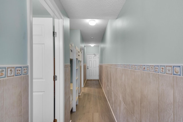1200 Scenic Gulf Dr Unit B507, Miramar Beach, FL 32550 - hall featuring wainscoting, tile walls, wood finished floors, and a textured ceiling