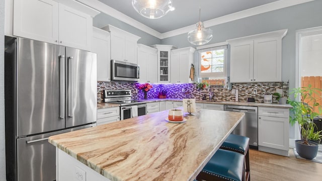995 Airport Rd Unit 28, Destin, FL 32541 - kitchen featuring appliances with stainless steel finishes, light countertops, white cabinetry, decorative light fixtures, and glass insert cabinets