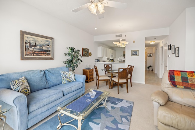 living room with light carpet, ceiling fan, a chandelier, and baseboards