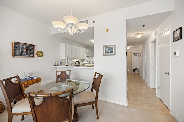 dining space with a chandelier, baseboards, and light colored carpet