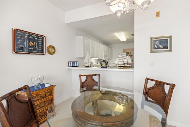 dining room featuring a chandelier, light colored carpet, and baseboards