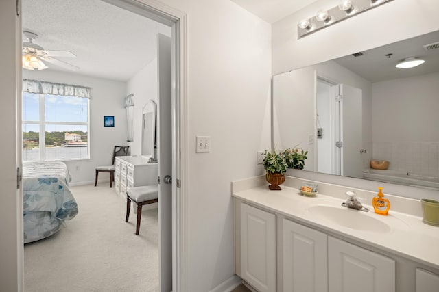 ensuite bathroom featuring vanity, a ceiling fan, and baseboards