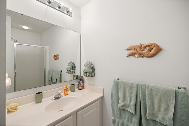 full bath featuring a stall shower, vanity, and a textured ceiling