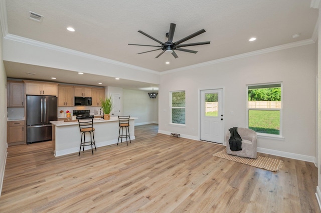 kitchen with black appliances, a ceiling fan, an island with sink, light wood-type flooring, and crown molding