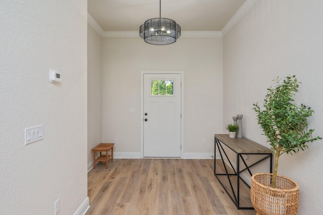 entryway with light wood-style floors, ornamental molding, and baseboards
