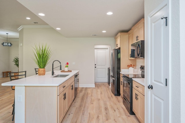 kitchen with black appliances, a sink, a kitchen island with sink, a kitchen bar, and light wood-style floors