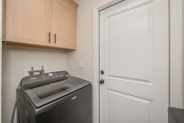 clothes washing area with washer / dryer and cabinet space