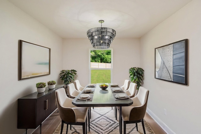 dining room featuring a chandelier, wood finished floors, and baseboards